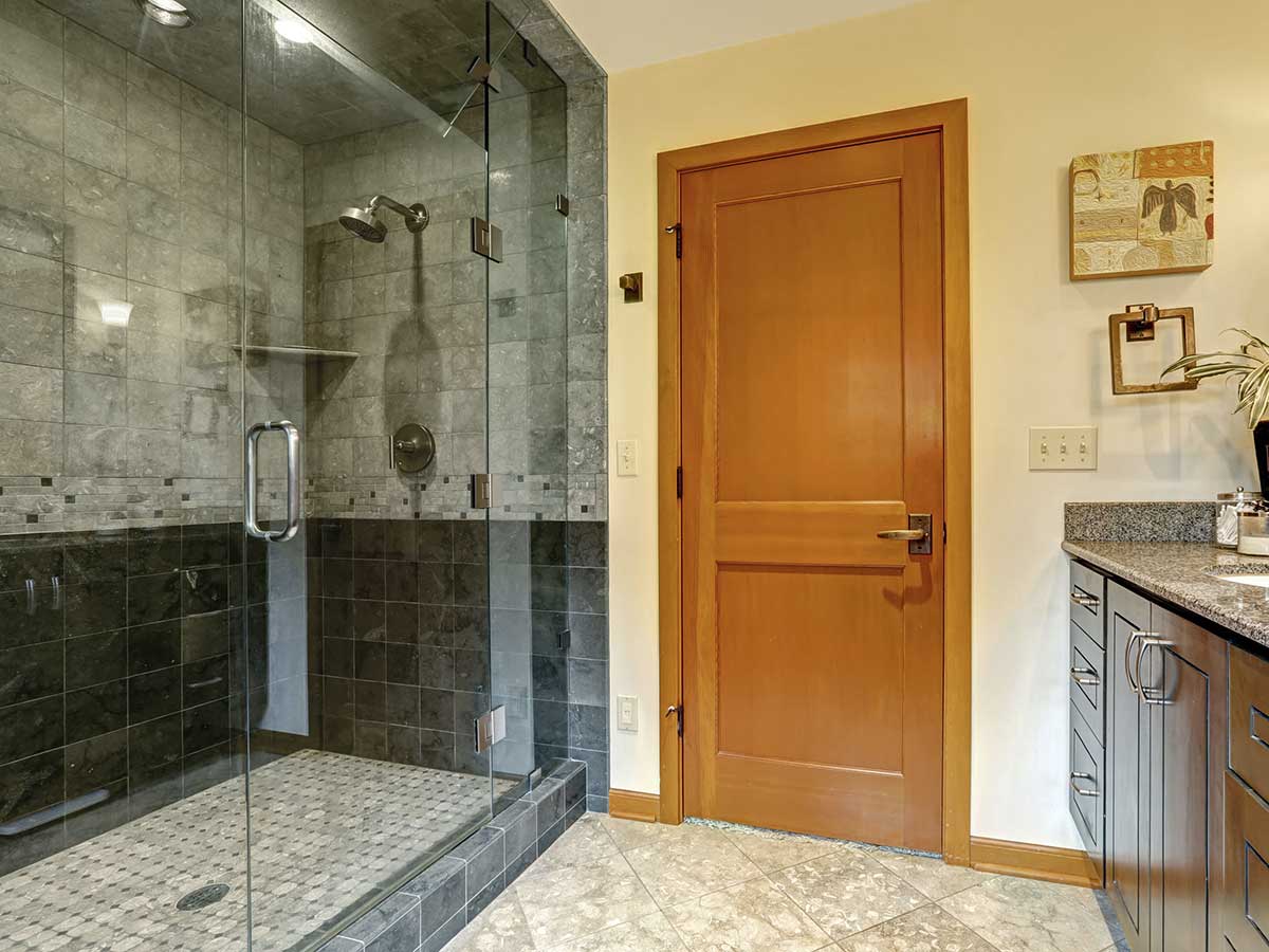 Modern bathroom with glass shower enclosures and wood cabinets